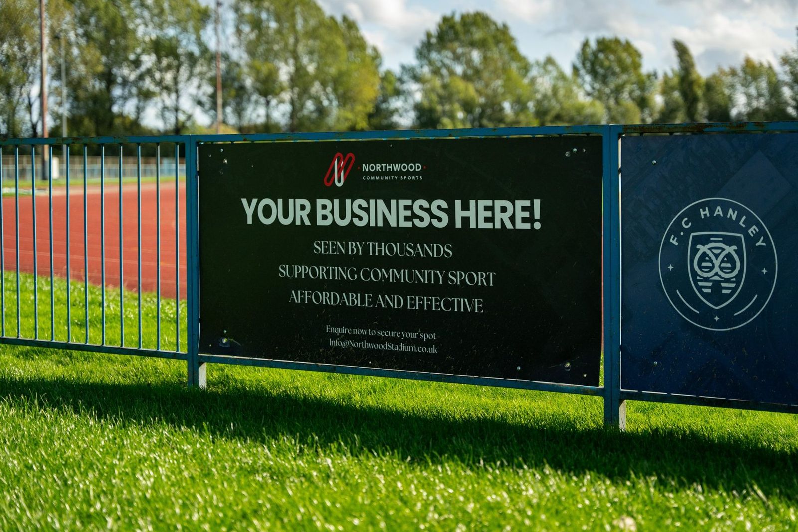 A 'Your Business Here' sponsor board beside the Northwood track